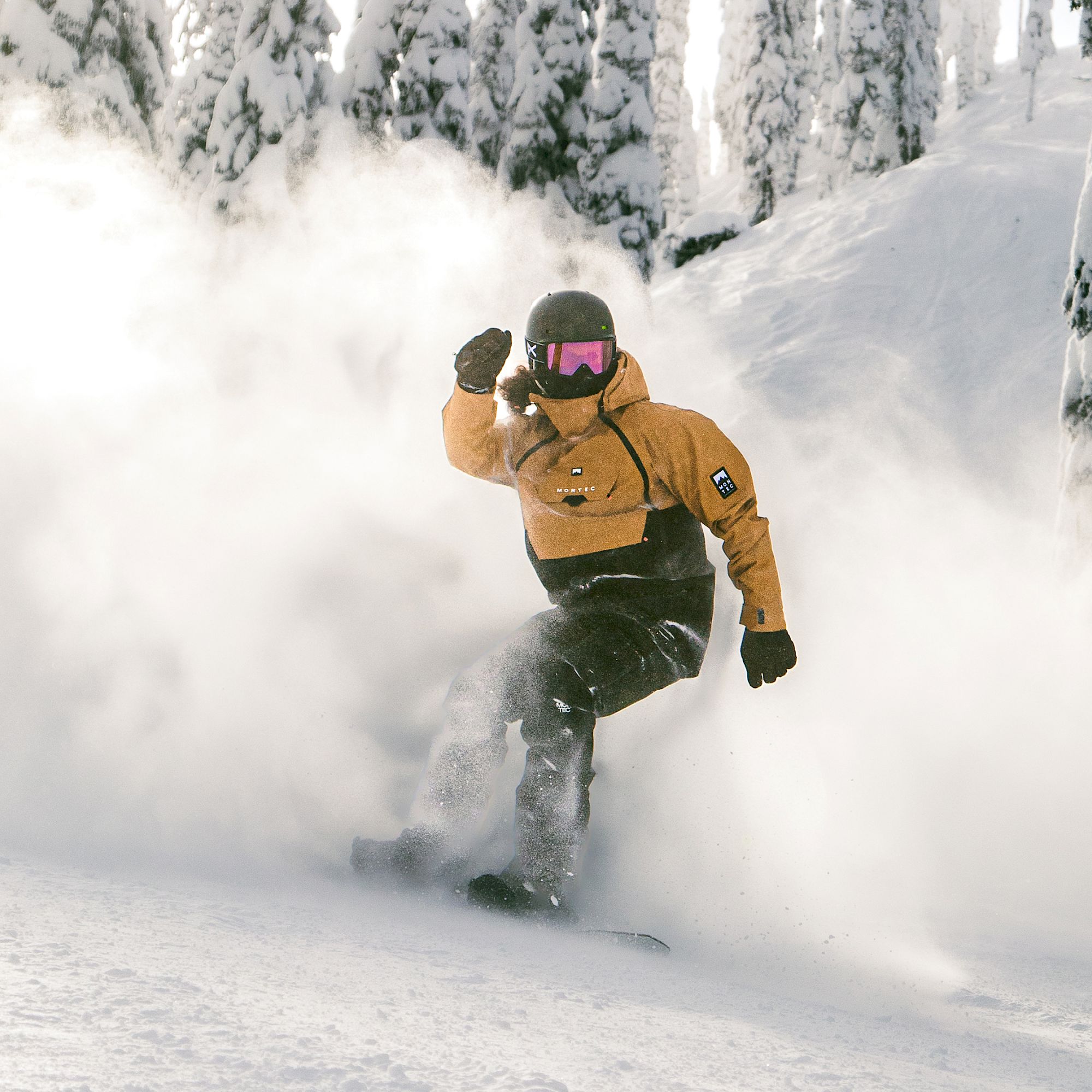 Alex Volokhov snowboarding at Whitewater with a trail of powder flying behind him.